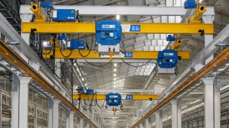 Beberapa unit ABUS overhead crane berwarna kuning beroperasi secara berurutan pada satu runway di dalam pabrik, menunjukkan kondisi operasional yang membutuhkan anti-collision device