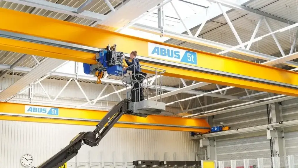 Teknisi di platform kerja memeriksa hoist pada girder crane ABUS berkapasitas 5 ton di dalam pabrik.